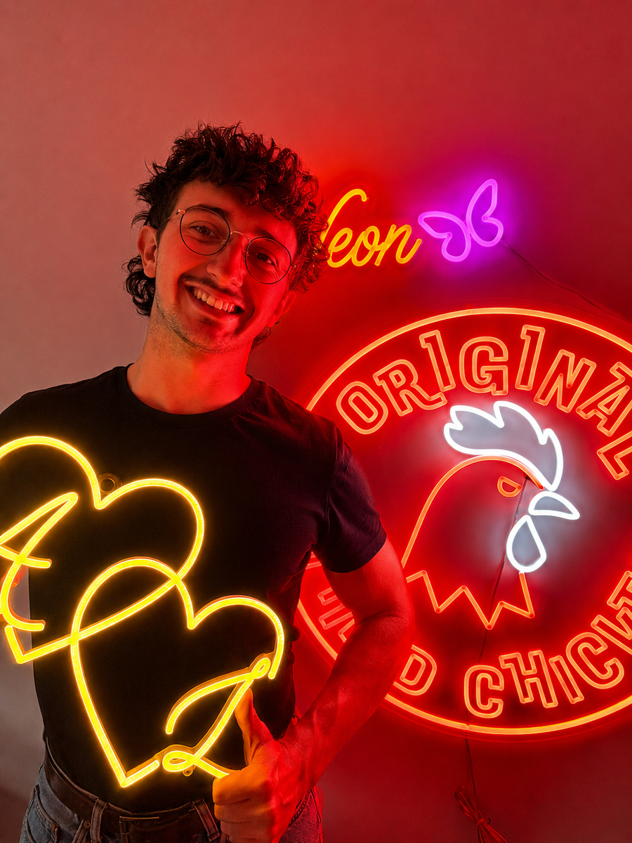 Pablo, conseiller Lumicorne, devant des enseignes lumineuses sur-mesure